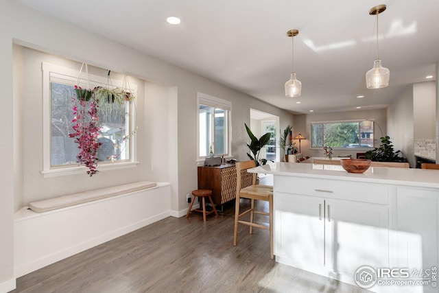kitchen featuring recessed lighting, light countertops, white cabinets, light wood finished floors, and hanging light fixtures