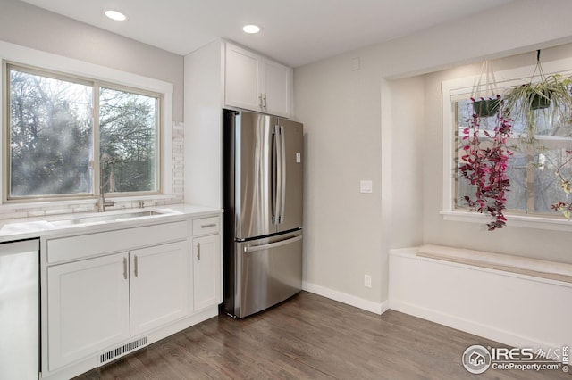 kitchen featuring visible vents, a sink, baseboards, freestanding refrigerator, and white cabinetry