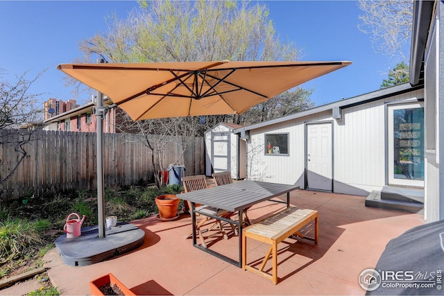 view of patio with a storage shed, outdoor dining space, an outdoor structure, and a fenced backyard