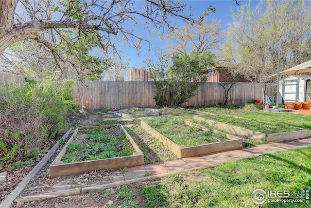 view of yard with a fenced backyard, a garden, a shed, and an outbuilding