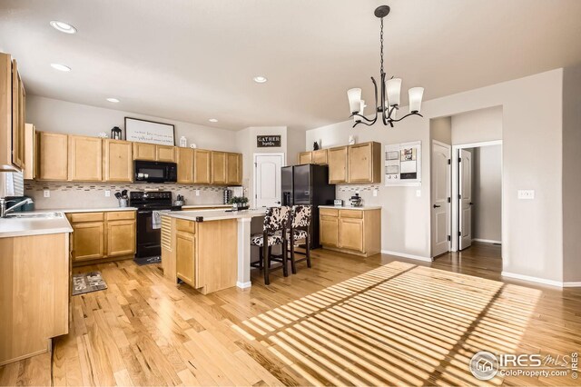 273 Mt Harvard Ave, Severance, CO 80550 - kitchen with decorative backsplash, light brown cabinets, a center island, a sink, and black appliances