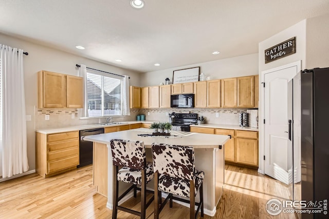 273 Mt Harvard Ave, Severance, CO 80550 - kitchen featuring light countertops, light brown cabinetry, a breakfast bar, and black appliances
