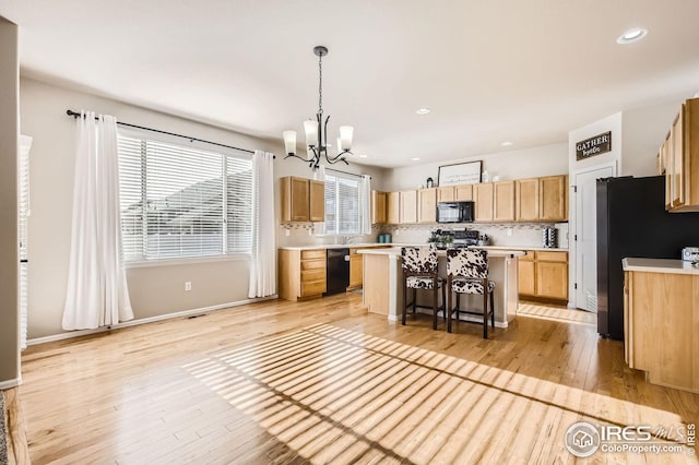 273 Mt Harvard Ave, Severance, CO 80550 - kitchen featuring a breakfast bar area, a notable chandelier, black appliances, and light countertops