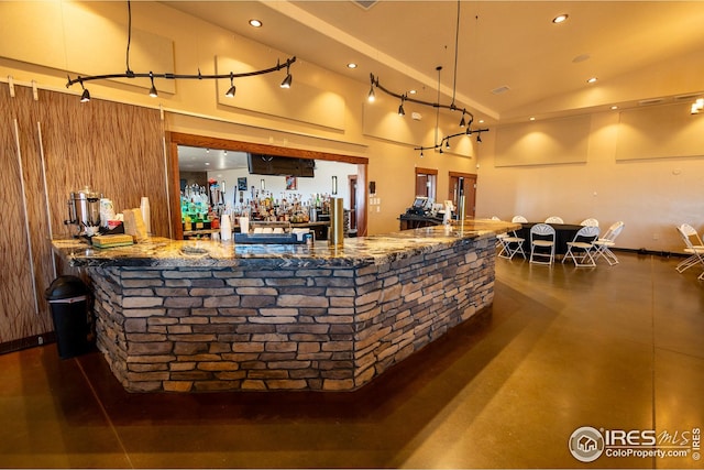 interior space with a bar, high vaulted ceiling, concrete flooring, and recessed lighting