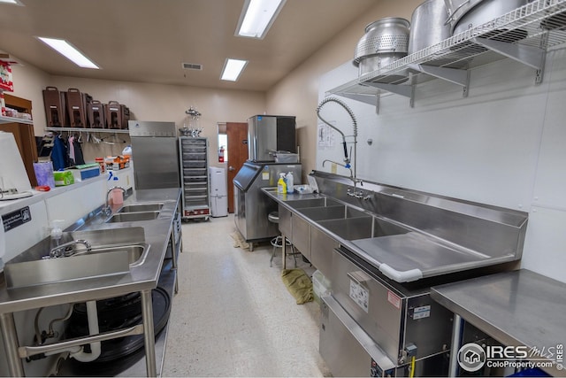 kitchen with visible vents, a sink, open shelves, and stainless steel countertops
