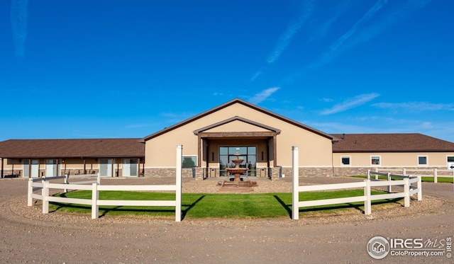 view of front facade featuring fence, stone siding, and stucco siding