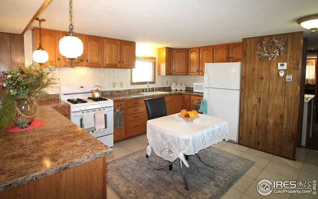kitchen featuring white appliances, light tile patterned flooring, a sink, brown cabinets, and backsplash
