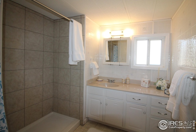 bathroom featuring tiled shower, vanity, and tile walls