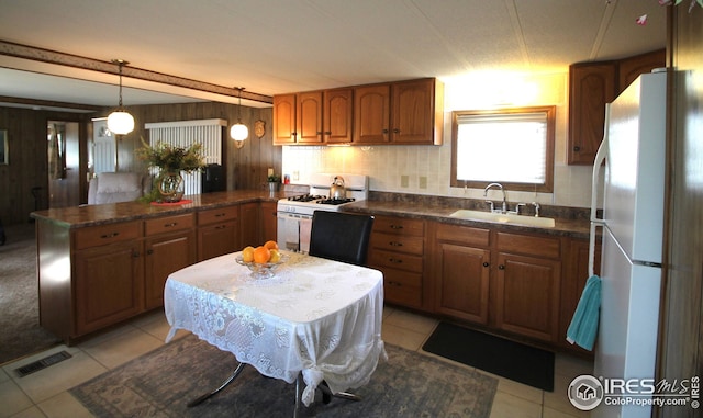 kitchen featuring white appliances, a peninsula, visible vents, brown cabinetry, and a sink
