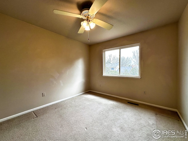 carpeted spare room with ceiling fan, baseboards, and visible vents