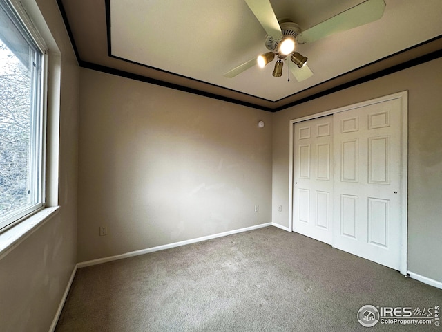 unfurnished bedroom with a closet, carpet flooring, baseboards, and multiple windows