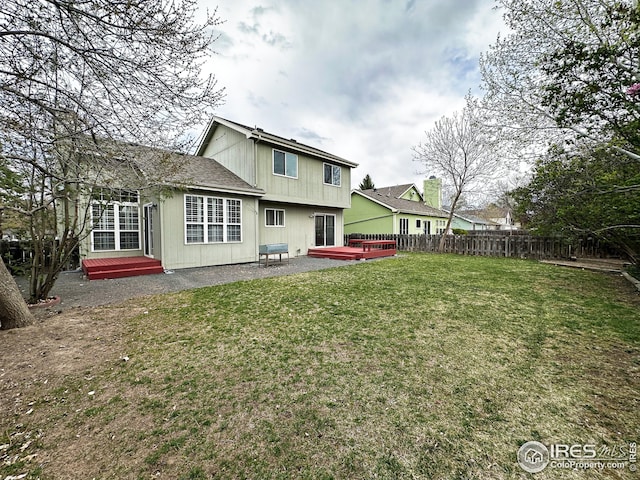 back of house featuring a lawn, a wooden deck, fence, and a patio area