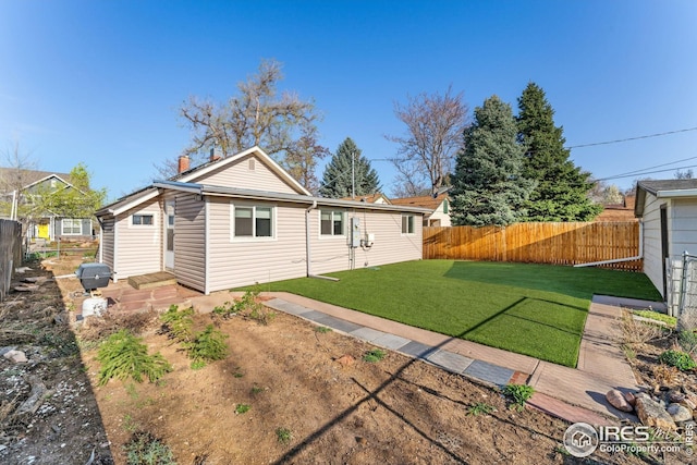 back of house featuring a yard and a fenced backyard