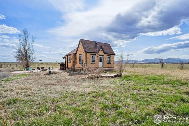 view of front of house featuring a rural view, a mountain view, and brick siding