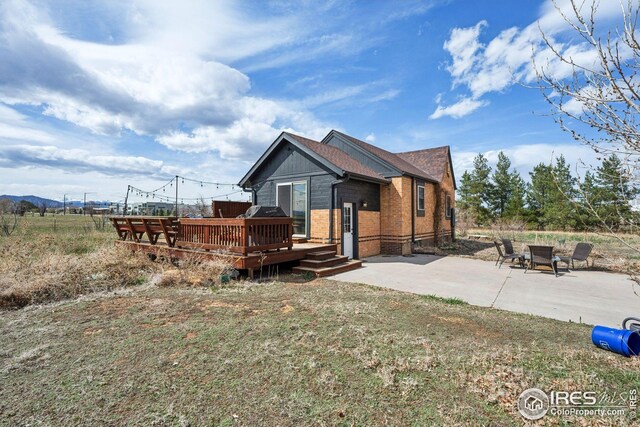 back of property featuring a patio area, a wooden deck, and brick siding