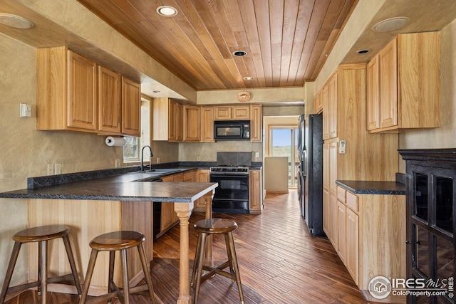 kitchen featuring a peninsula, black appliances, wood ceiling, dark wood-style flooring, and a sink