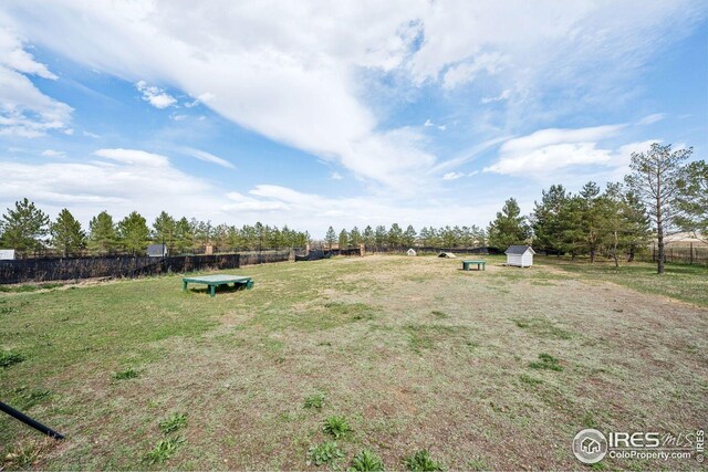 view of yard featuring a shed, fence, and an outbuilding