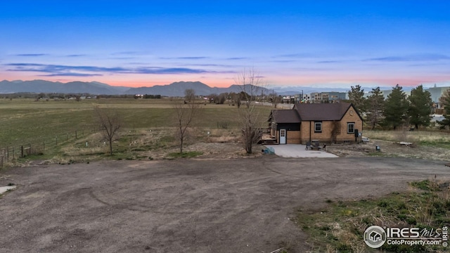 view of front of home with a rural view, a mountain view, and fence