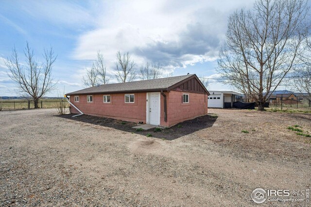 exterior space with concrete block siding, fence, an outdoor structure, and roof with shingles