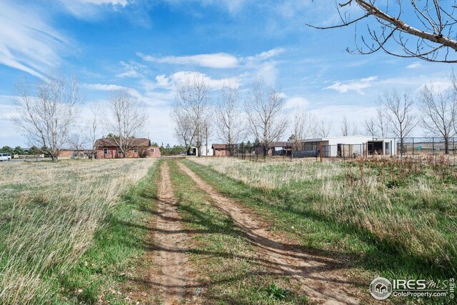 view of street with a rural view and dirt driveway