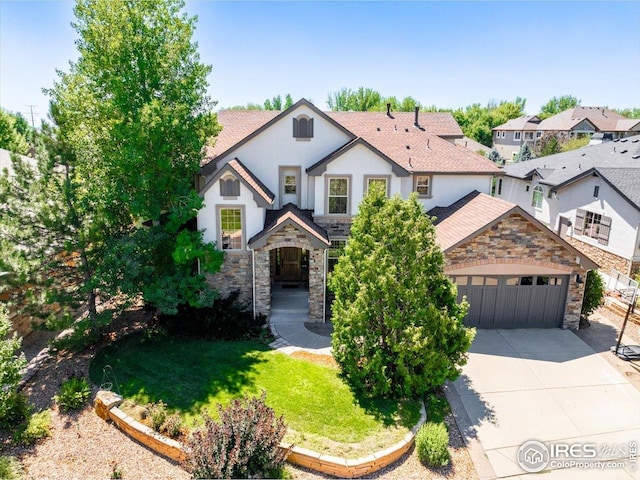 view of front of home featuring an attached garage, stone siding, driveway, and stucco siding
