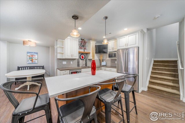 kitchen with tasteful backsplash, white cabinetry, a sink, stainless steel appliances, and baseboards