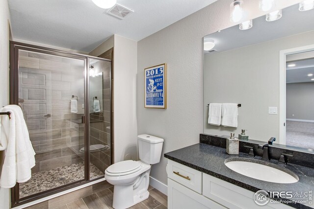 16335 Spanish Peak Way, Broomfield, CO 80023 - bathroom with toilet, a stall shower, vanity, baseboards, and visible vents