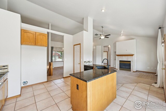 kitchen with dark stone countertops, light colored carpet, a sink, and lofted ceiling