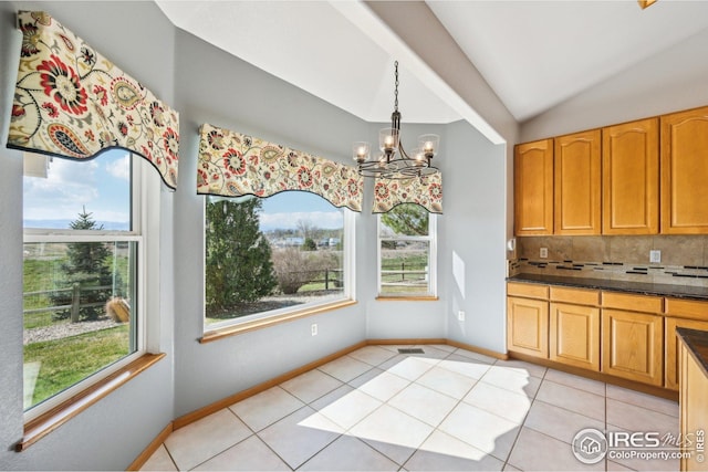unfurnished dining area with light tile patterned floors, plenty of natural light, a notable chandelier, and lofted ceiling