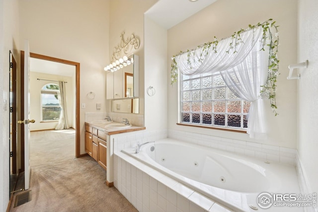 full bathroom with vanity, a tub with jets, and visible vents