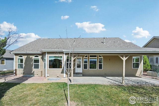 back of property featuring a yard, fence, a shingled roof, and a patio