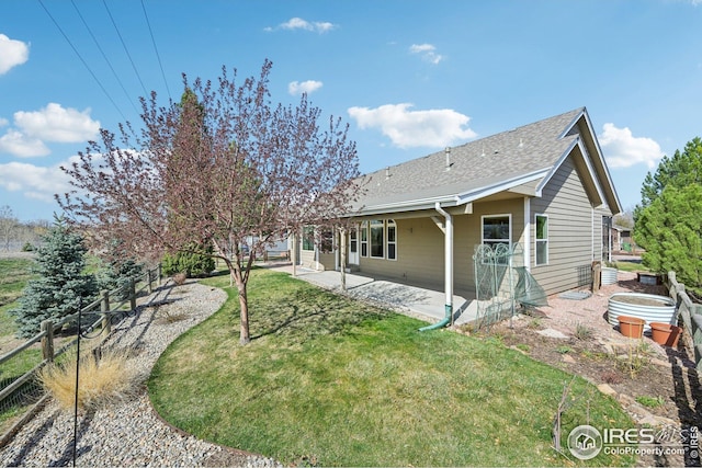 rear view of house featuring a patio area, roof with shingles, a yard, and fence