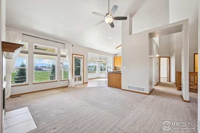 unfurnished living room featuring light carpet, visible vents, ceiling fan with notable chandelier, and baseboards