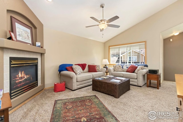 carpeted living room with ceiling fan, a tiled fireplace, and vaulted ceiling