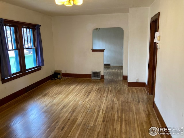 unfurnished room with baseboards, visible vents, and wood finished floors