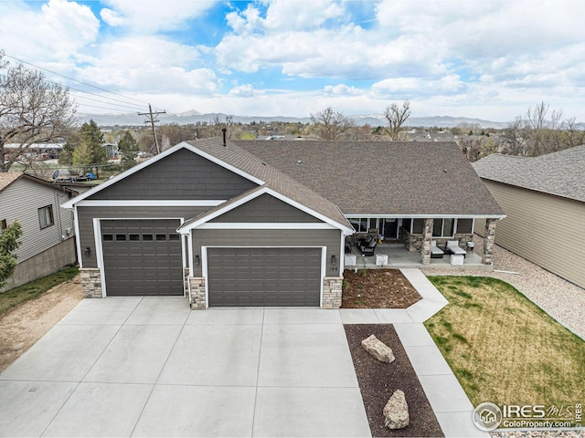 craftsman-style house with stone siding, concrete driveway, a mountain view, and a garage