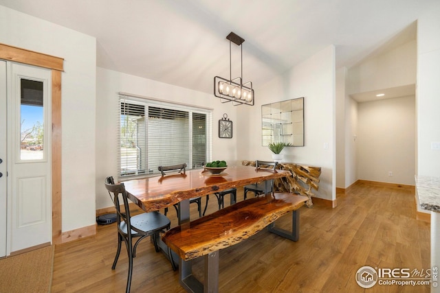 dining area featuring light wood-style floors, vaulted ceiling, and baseboards