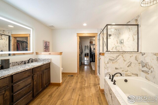 full bath featuring a shower stall, a garden tub, wood finished floors, and visible vents