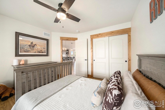 bedroom with a closet, wood finished floors, visible vents, and ceiling fan