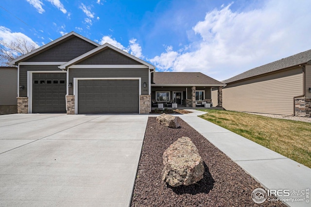 craftsman house with driveway, a porch, stone siding, and a garage
