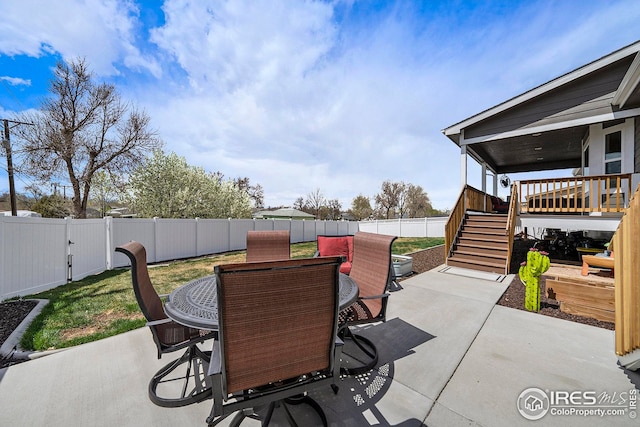 view of patio with stairway, a fenced backyard, outdoor dining area, and a deck