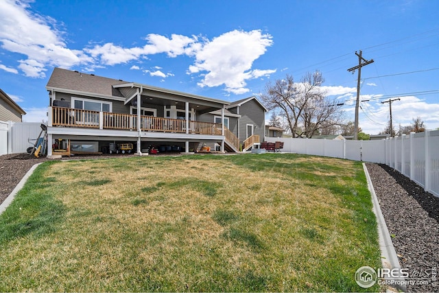 rear view of house with stairway, a wooden deck, a fenced backyard, and a yard