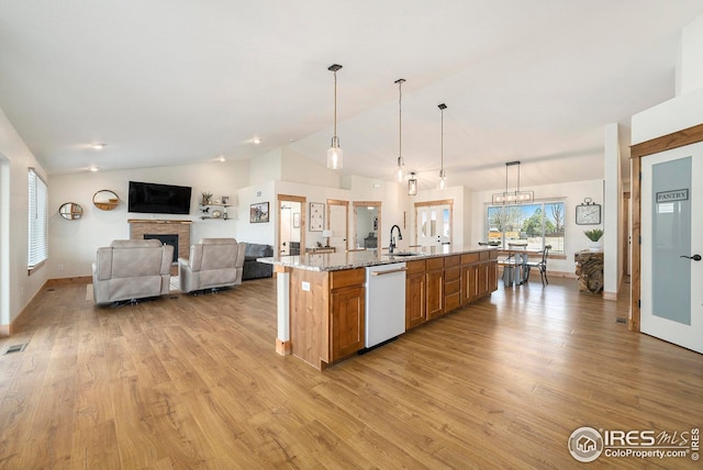 kitchen featuring light wood finished floors, a sink, vaulted ceiling, white dishwasher, and brown cabinetry