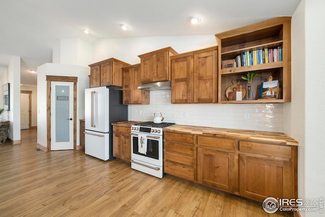 kitchen with under cabinet range hood, vaulted ceiling, white appliances, butcher block counters, and tasteful backsplash
