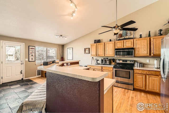 kitchen with stainless steel appliances, light countertops, rail lighting, a center island, and ceiling fan