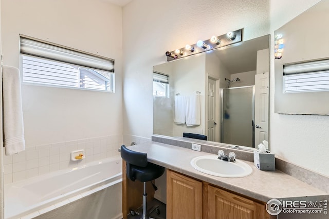 full bathroom featuring a shower stall, a bath, and vanity