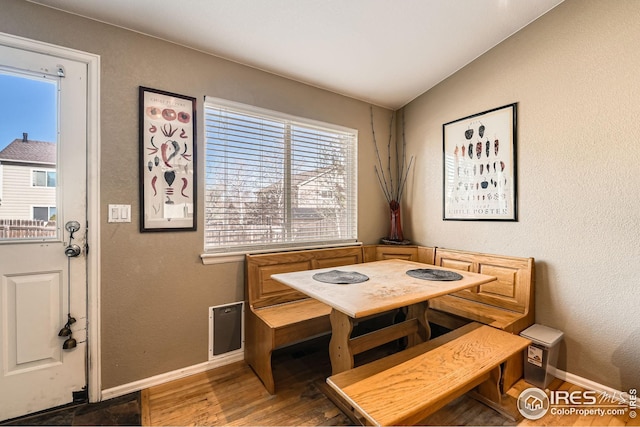 dining space with wood finished floors, baseboards, and a textured wall