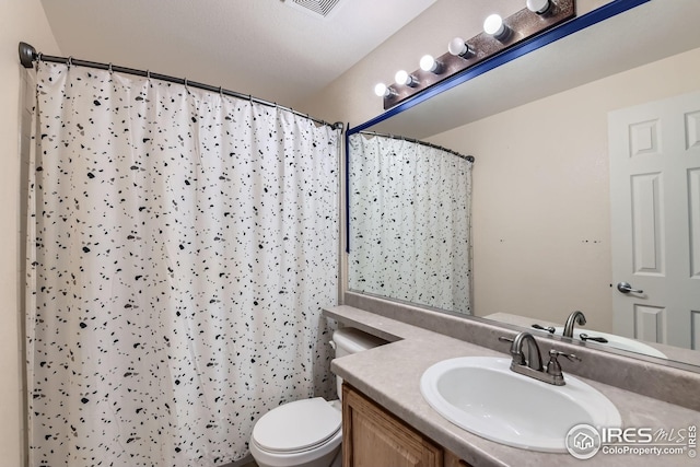 bathroom with curtained shower, toilet, and vanity