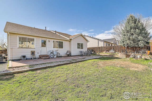 rear view of property featuring entry steps, a patio area, a lawn, and fence