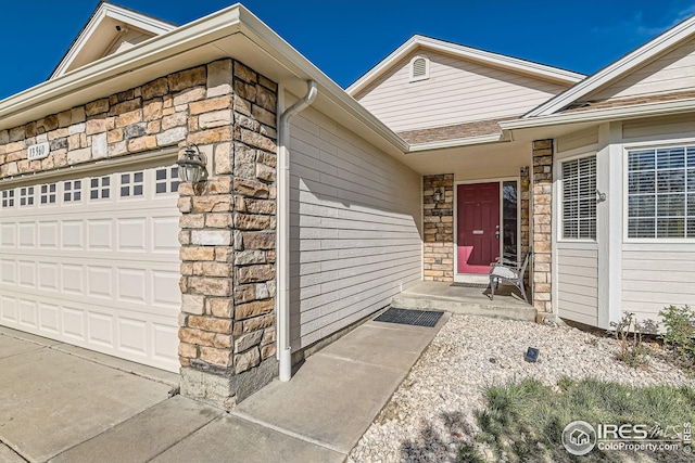 entrance to property featuring stone siding and a garage